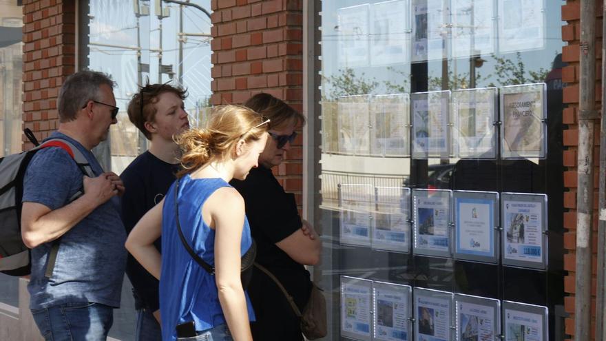 Una familia extranjera observa los precios de los pisos en València. G caballero