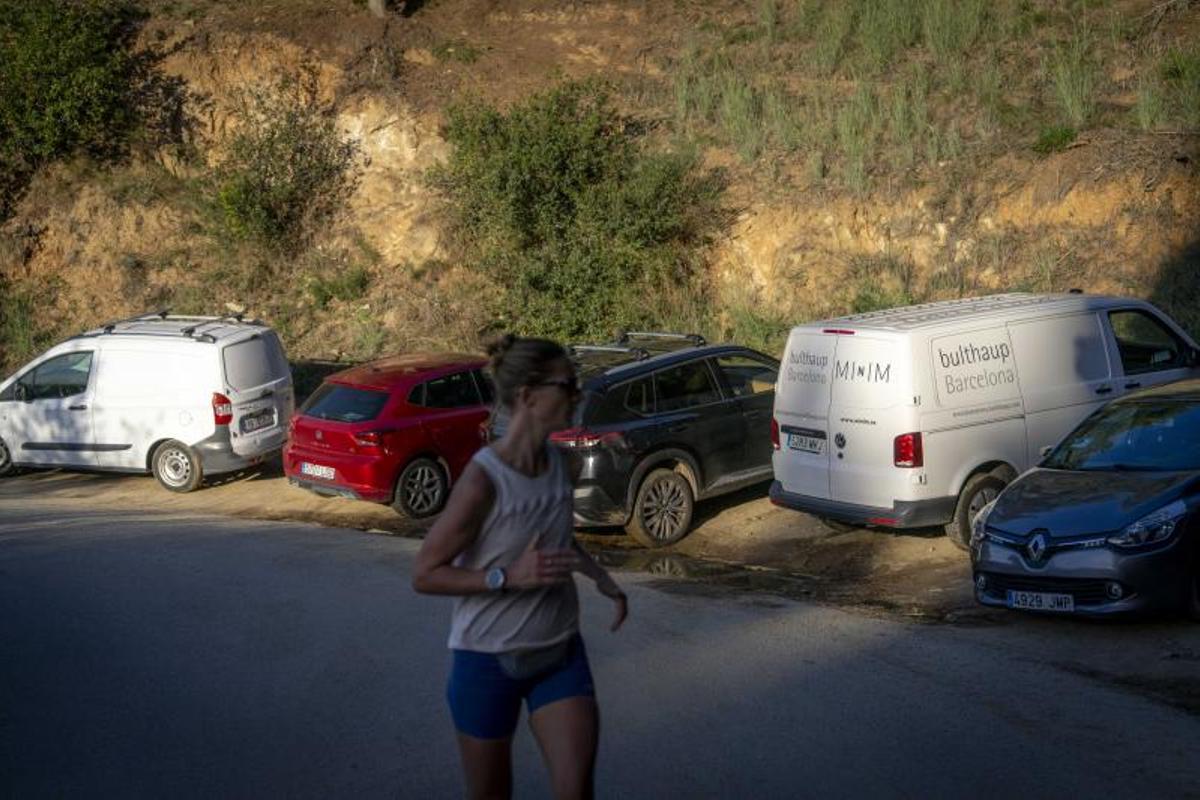 Una muje corre junto a vehículos aparcados donde no pueden estarlo, el pasado viernes.