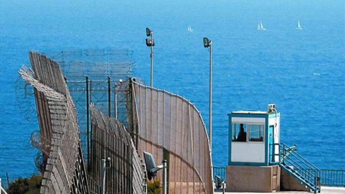 Unos barcos de vela navegan frente a la valla fronteriza que separa Melilla de Marruecos.