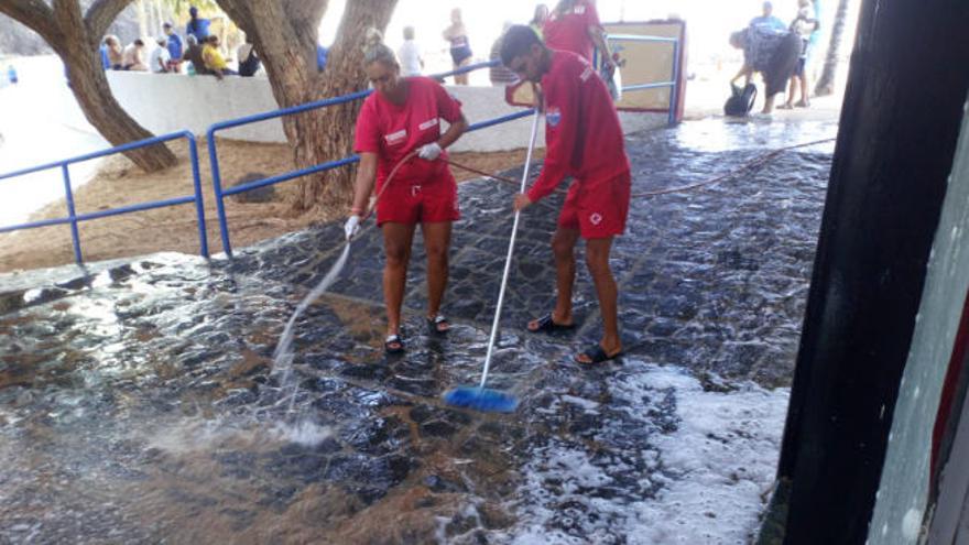 Dos trabajadores de Cruz Roja limpiando el exterior de su puesto.