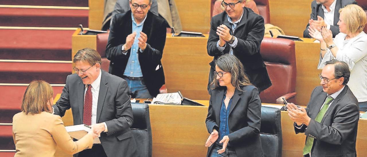 El presidente Puig saluda a Isabel Bonig en las Cortes en presencia de Mónica Oltra, líder de Compromís.