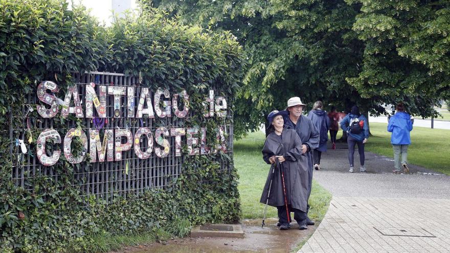 Dúas persoas posan xunto ao cartel que da a benvida á cidade aos peregrinos través do Camiño Francés / |  A. HERNÁNDEZ