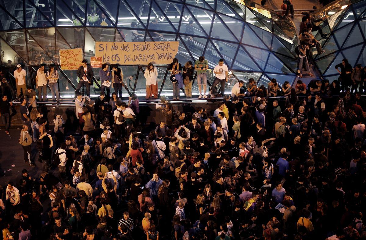 La entrada del metro en Sol rodeada de 'indignados' donde se puede leer una pancarta con una de las frases de la acampada del 15-M.
