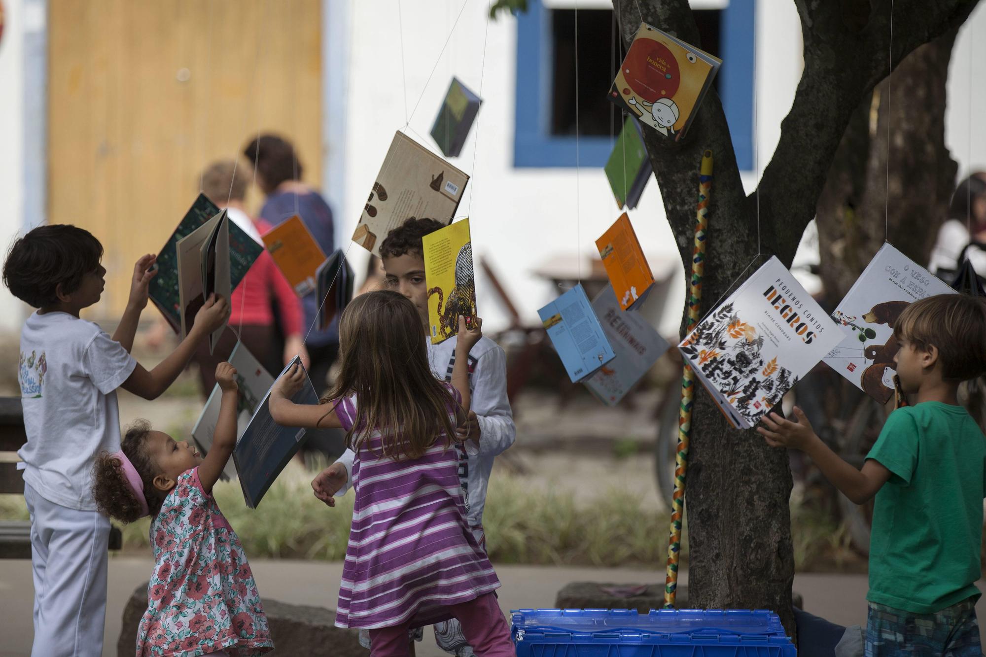 Un grupo de niños observa libros colgados en los árboles de la plaza de la Matriz, en la realización de la 13 edición de la Fiesta Literaria Internacional de Paraty (FLIP), en la ciudad de Paraty (Brasil).