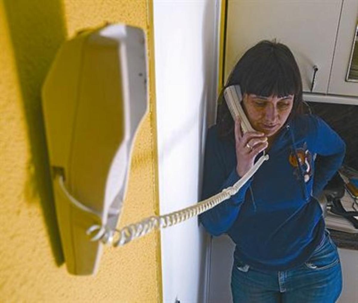 Una mujer habla utilizando un teléfono fijo.