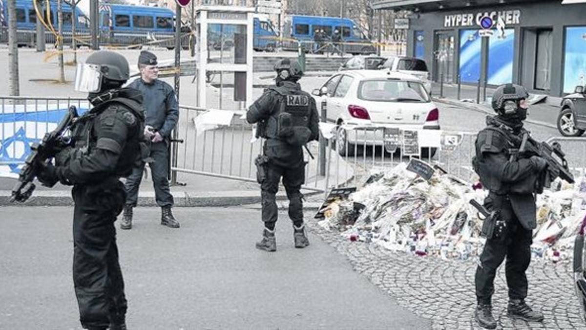 Las fuerzas especiales francesas desplegadas junto al supermercado donde fueron asesinados cuatro rehenes judíos, recordados con flores y la bandera israelí.