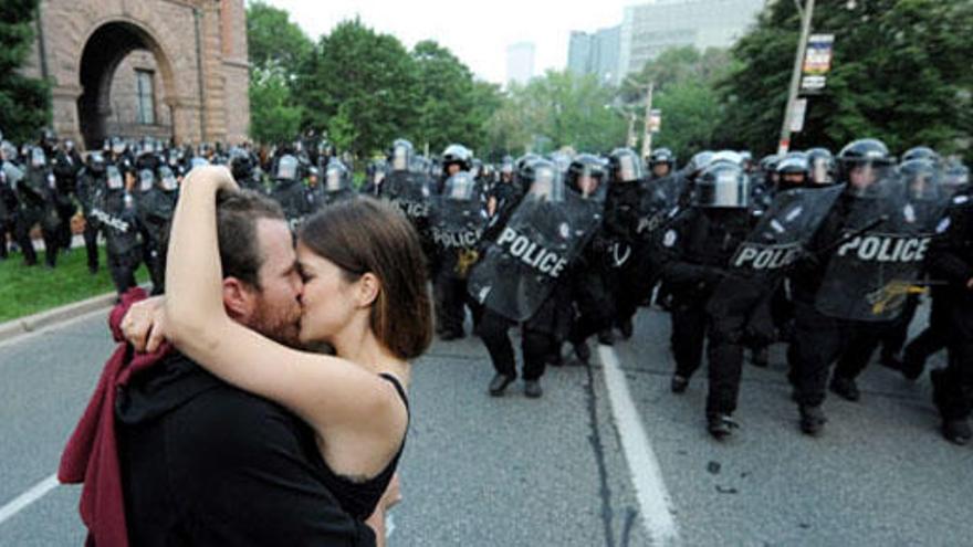 Dos manifestantes se besan delante de la policía.