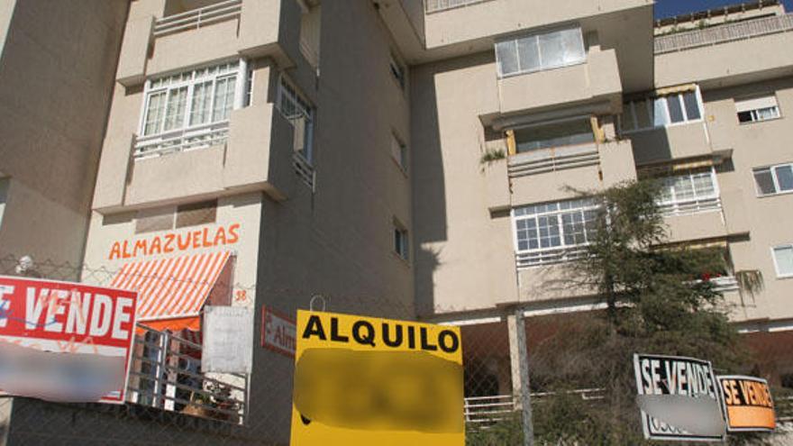 Carteles de pisos y locales en venta y alquiler en un edificio de Málaga.