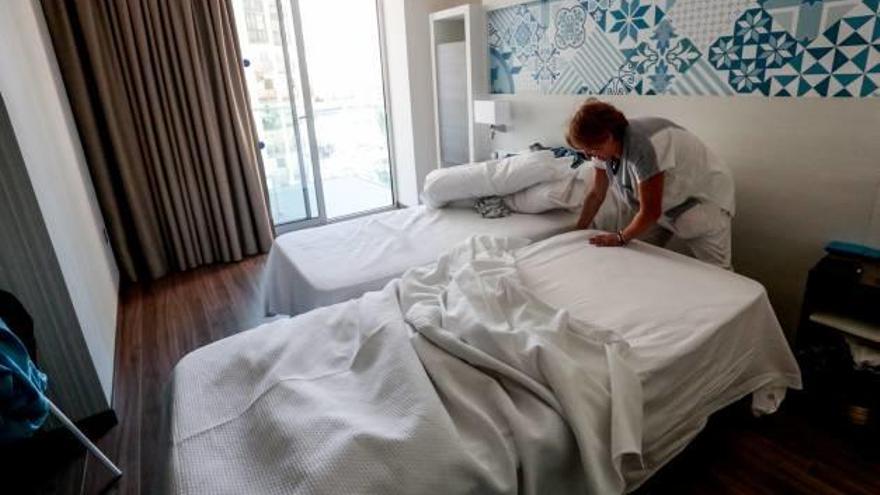 Una camarera cambiando la ropa de cama de la habitación de un hotel en Benidorm.