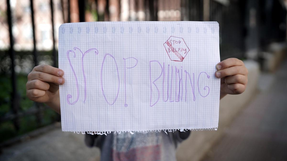 Un niño muestra un cartel para terminar con el bullying.