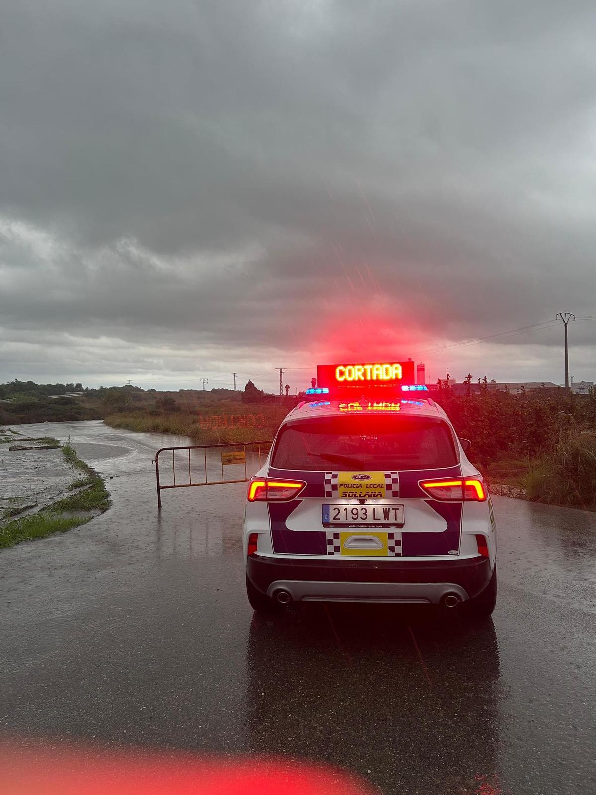 La Policía Local de Sollana señaliza un camino cortado por el agua, esta mañana.