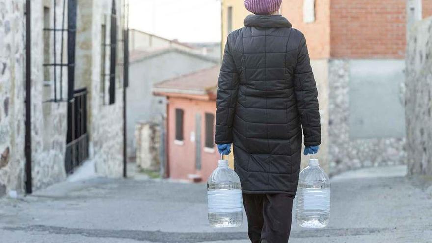 Una vecina de Tardobispo carga con dos garrafas de las que facilitaba la Diputación antes de la conexión con la red de Zamora.