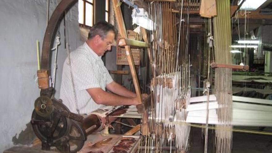 Un trabajador muestra cómo funcionan los telares históricos.
