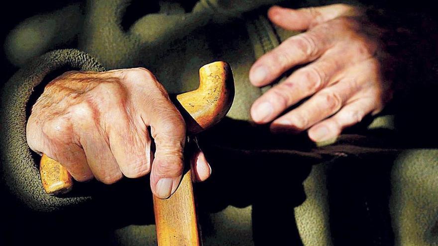 Las manos de una persona mayor con un bastón.