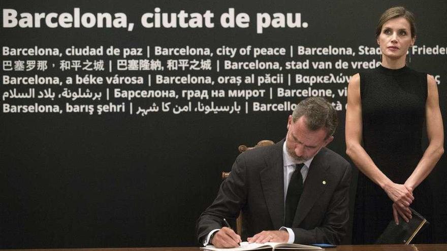 Los Reyes firman en el libro de condolencias abierto en el consistorio barcelonés. // Reuters
