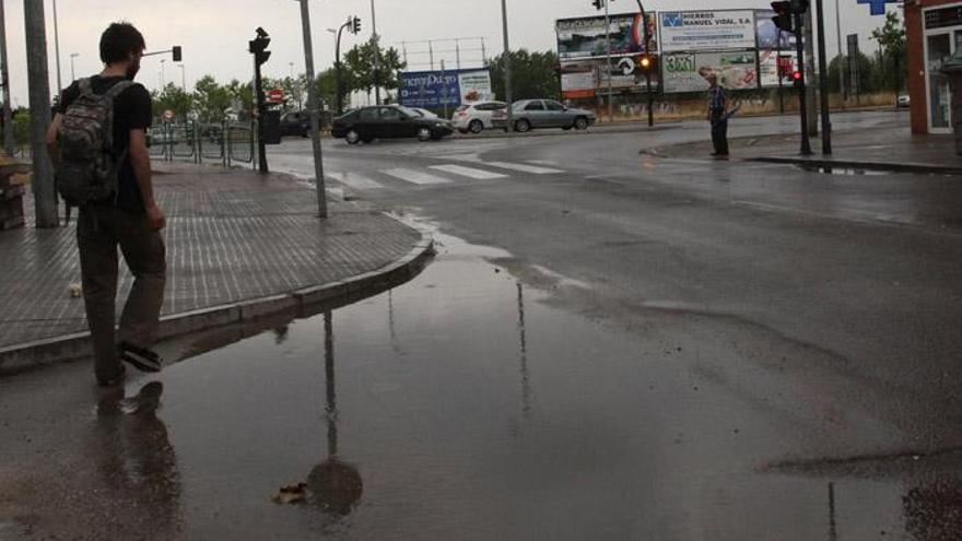 Un hombre camina sobre el asfalto mojado.