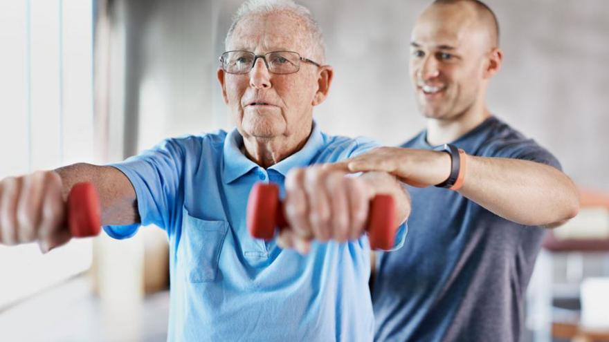 Un avi fent exercicis físics amb l’ajuda d’un entrenador.  | YURI ACURS / AP