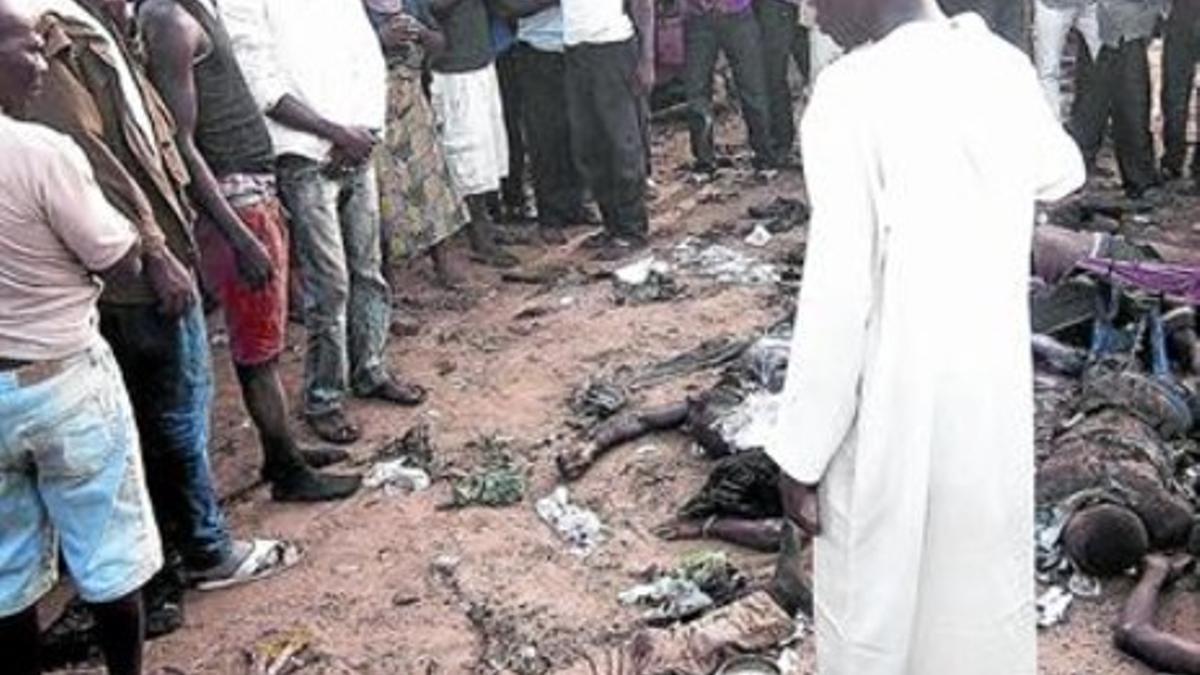 Un grupo de transeúntes contemplan horrorizados varios cadáveres tras el atentado de Abuya, el lunes.
