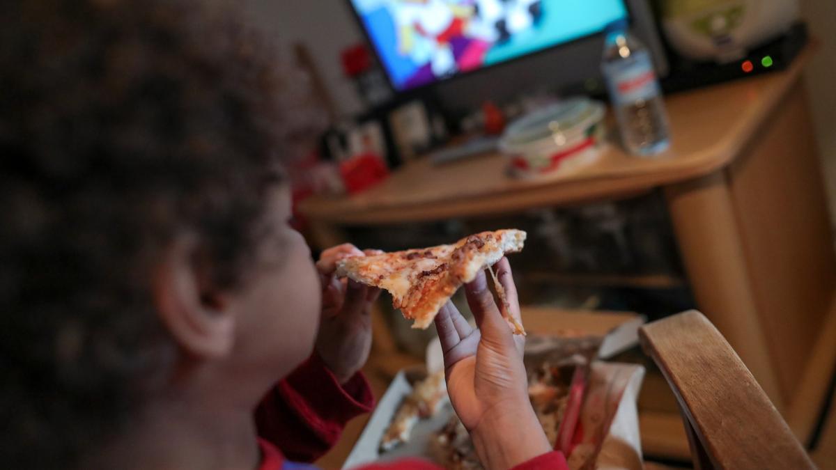 Un niño come un trozo de pizza. EP