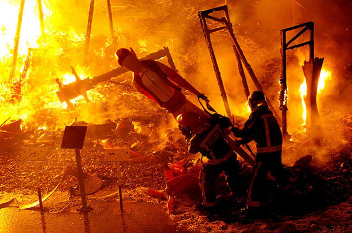 Els bombers llencen una figura que ha quedat exempta de cremar-se, durant les festes de les Fogueres de Sant Joan, a Alacant.