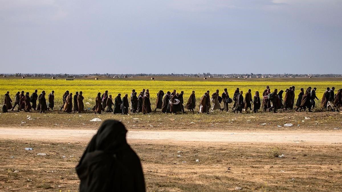 sospechosos de ser combatientes de IS del Estado Islámico caminan juntos hacia un punto de detección para los recién llegados dirigidos por las Fuerzas Democráticas Sirias