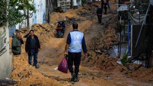 Un hombre vestido con una chaqueta de la agencia de la ONU para los refugiados palestinos (UNWRA) camina por una calle arrasada por las fuerzas israelíes  en Jenin.