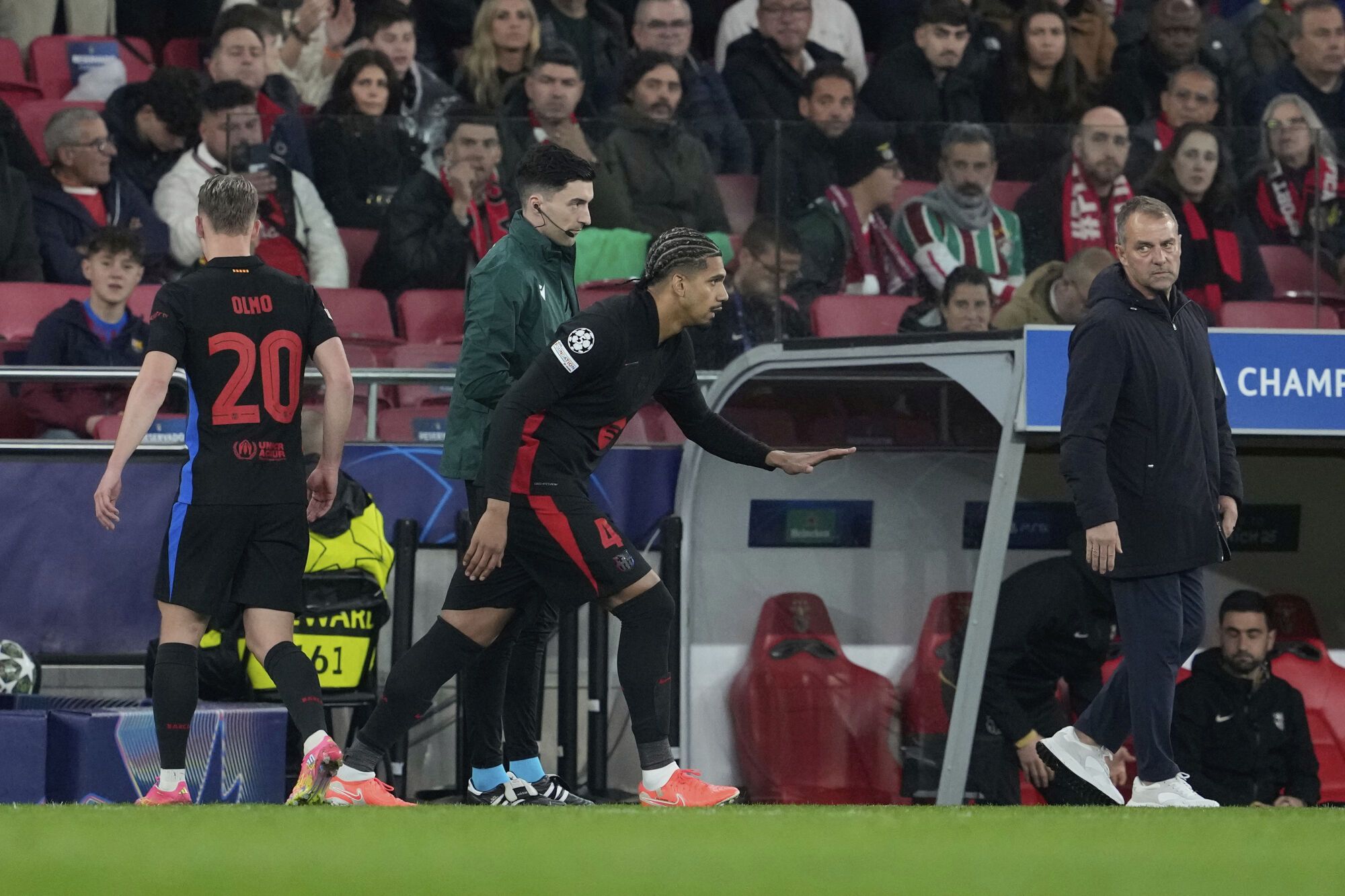 Barcelona's head coach Hansi Flick, right, looks on as Barcelona's Dani Olmo, left, is substituted by Barcelona's Ronald Araujo during the Champions League round of 16 first leg soccer match between SL Benfica and FC Barcelona at the Luz stadium in Lisbon, Wednesday, March 5, 2025. (AP Photo/Armando Franca)