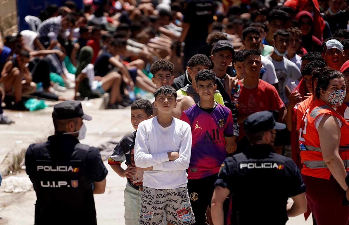 Menores migrantes no acompañados son custodiados por la policía en las naves industriales de Ceuta.