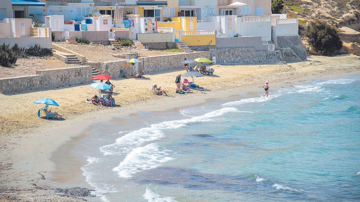 Veraneantes y vecinos de La Manga, en una de las zonas de playa que apenas tiene unos metros de superficie de arena, en una imagen realizada desde  el mirador del Galúa.