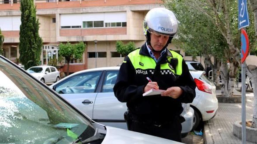 Un agent multa un vehicle que té la targeta caducada.