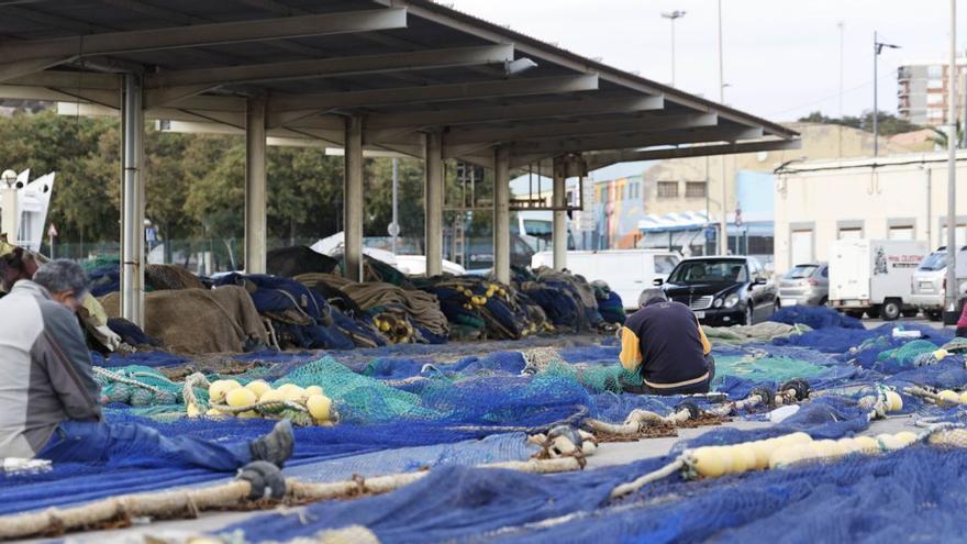 Pescadores reparan redes en el muelle de Santa Lucía, en el puerto de Cartagena. | IVÁN URQUÍZAR