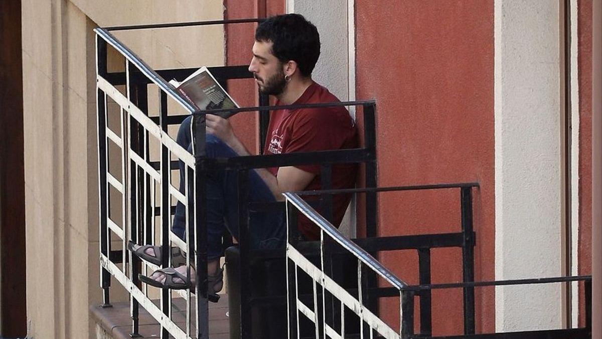 Un joven, leyendo en su balcón en Pamplona.