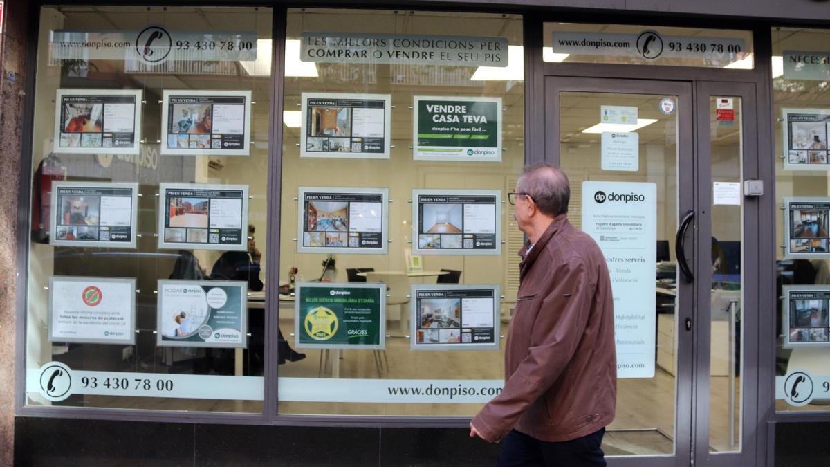 Un home passa per davant d'anuncis de la immobiliària Donpiso
