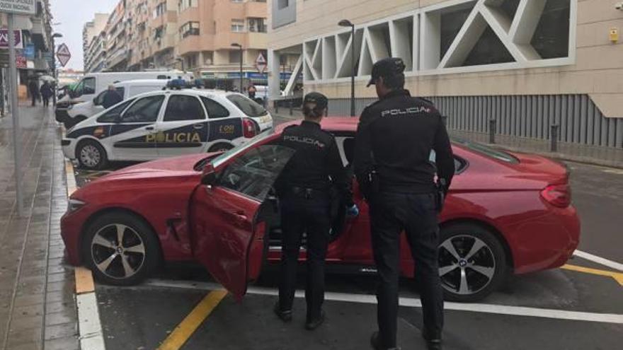 Dos policías observan el turismo BMW intervenido a la pareja detenida en Alicante.