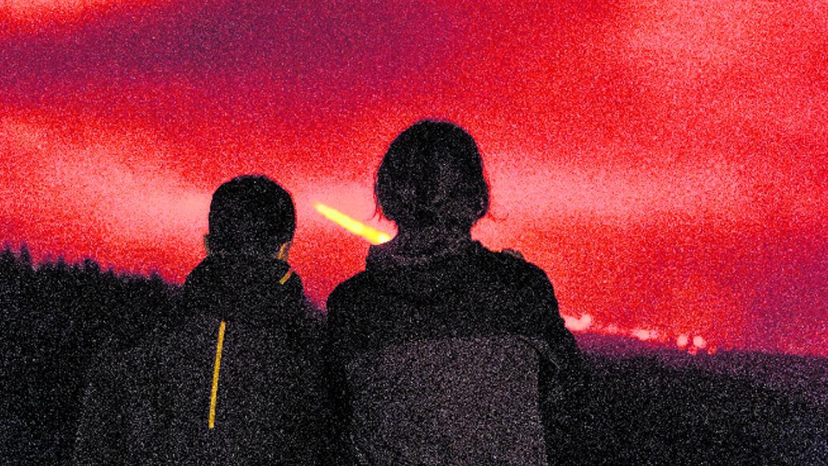 Dos personas observan el avance de la lava.