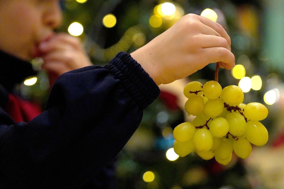 Un niño sostiene un racimo de uvas blancas, típicas de Nochevieja.