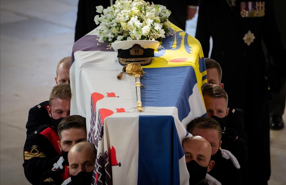 El féretro de Felipe de Edimburgo cubierto por su estandarte personal, una bandera que se basa en sus raíces griegas y danesas. Encima, su gorra naval y un ramo de flores blancas y la espada que ha lucido en algunos eventos ceremoniales.