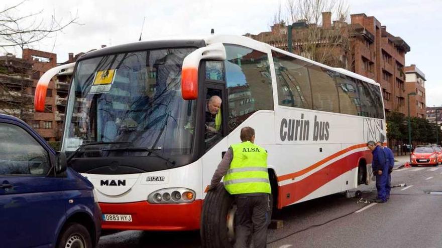 Varios trabajadores reparan el autobús de transporte escolar.