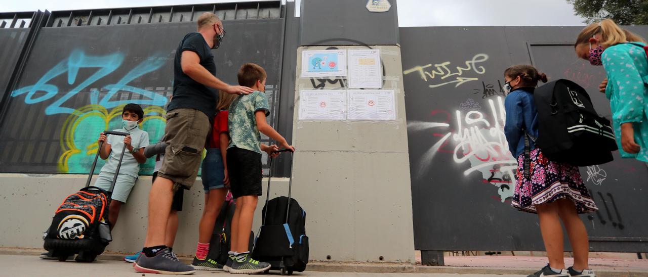 Un padre y varios alumnos leen las instrucciones contra el virus.