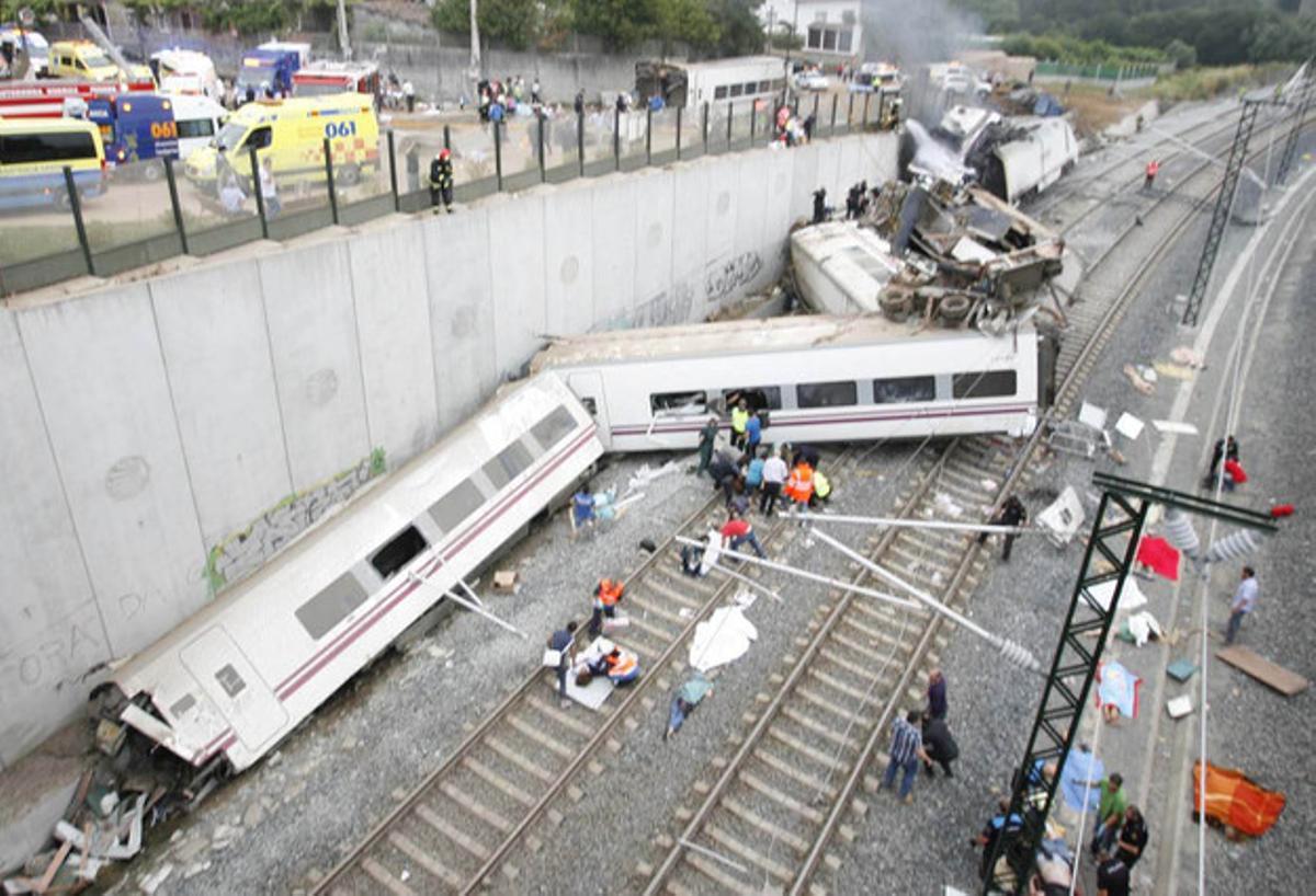 Diversos vagons del tren descarrilat al costat d’un mur de contenció.