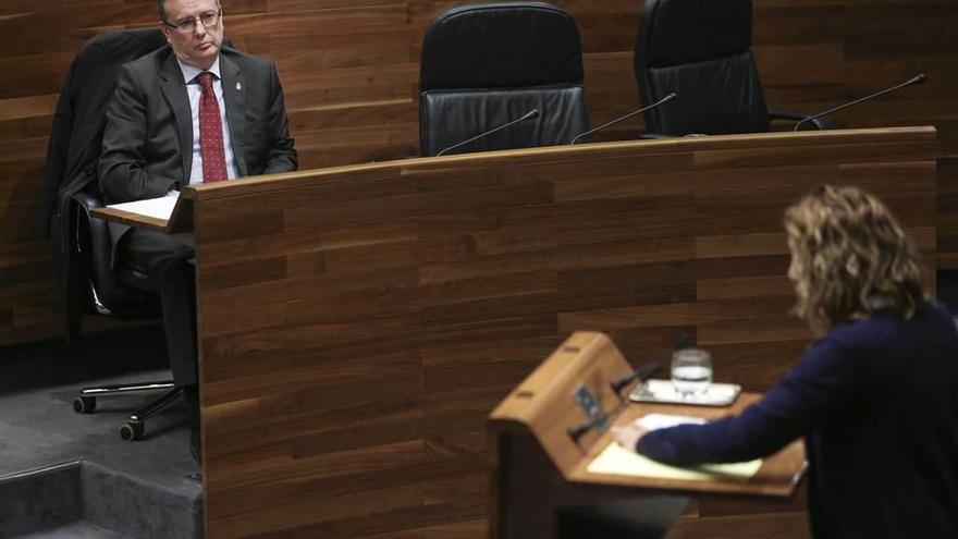 El consejero Francisco del Busto escucha a la diputada de Podemos Rosa Espiño en su pregunta sobre las cláusulas suelo, durante el Pleno de ayer en la Junta General.