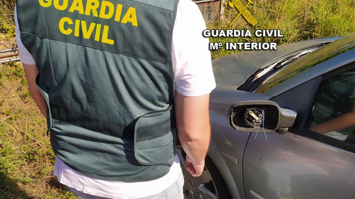 Un Guardia Civil junto a uno de los coches dañados supuestamente por los menores investigados.