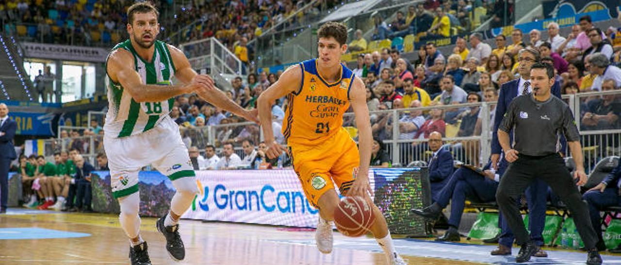 Oriol Paulí, jugador del Herbalife Gran Canaria, bota el balón defendido por Milosevic, del Betis.