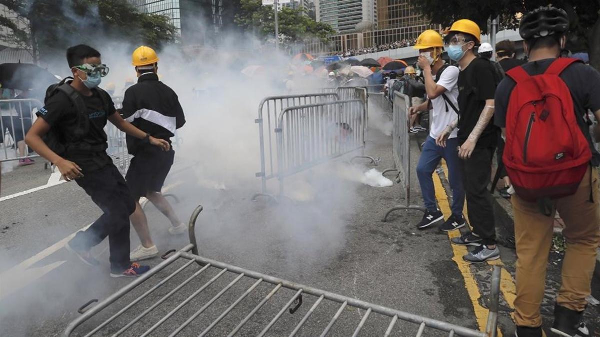 Un grupo de manifestantes reaccionan ante el lanzamiento de gas lacrimógeno durante una gran protesta contra la ley de extradición en los alrededores del Consejo Legislativo en Hong Kong.