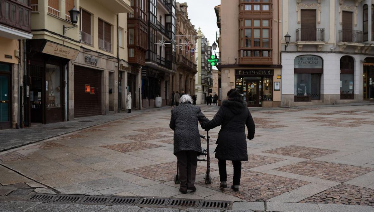 Dos personas atraviesan la Plaza Mayor. |