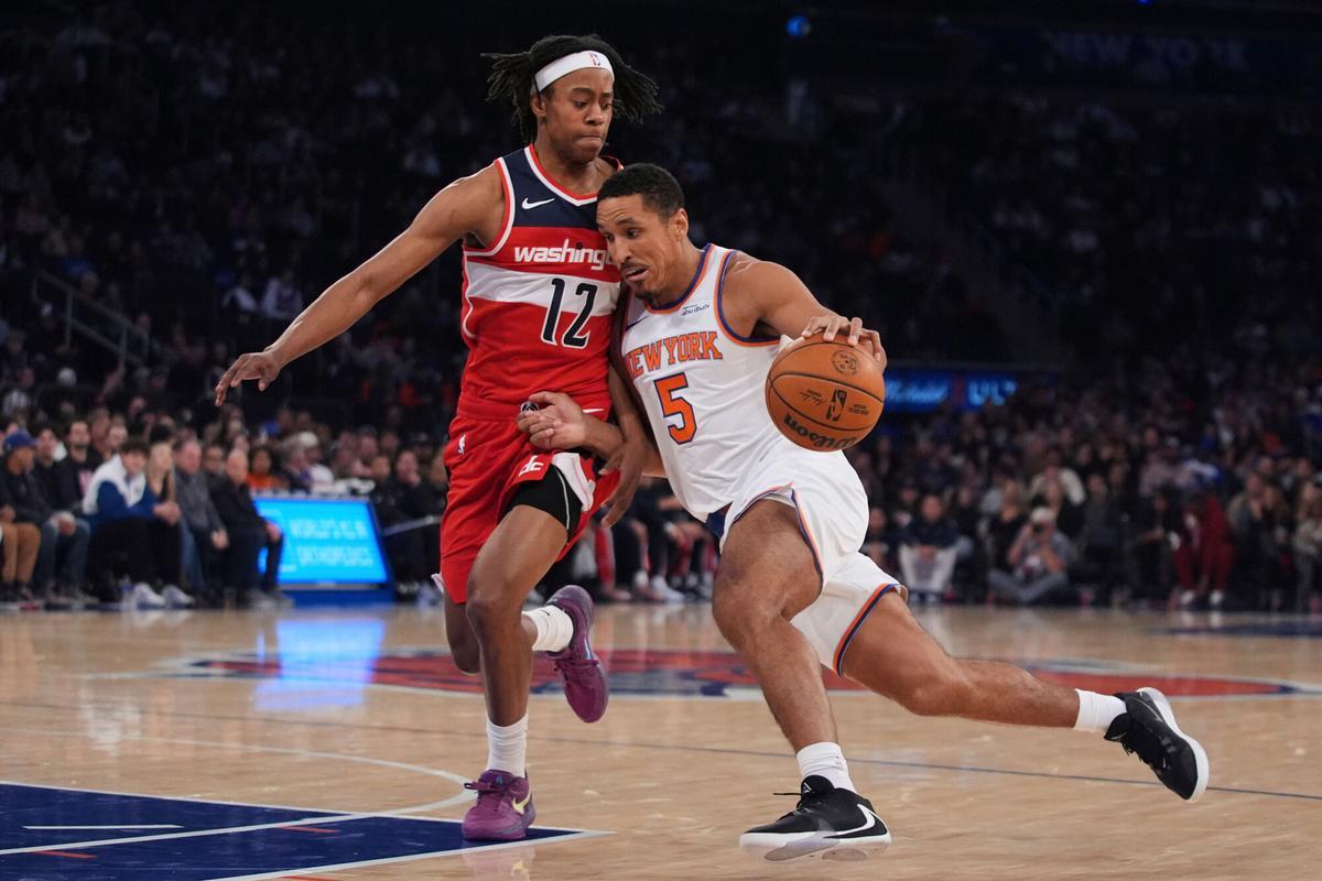 New York Knicks' Malcolm Brogdon (5) drives past Washington Wizards' Tre Johnson (12) during the first half of a preseason NBA basketball game Monday, Oct. 13, 2025, in New York. (AP Photo/Frank Franklin II)