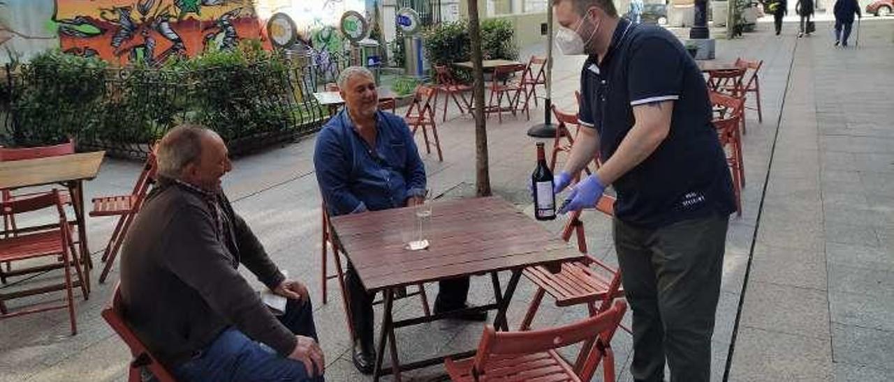 Jonathan Hernández sirve un vino a Mariano Pérez y Maximino Suárez en su terraza de la calle Jerónimo Ibrán de Mieres.