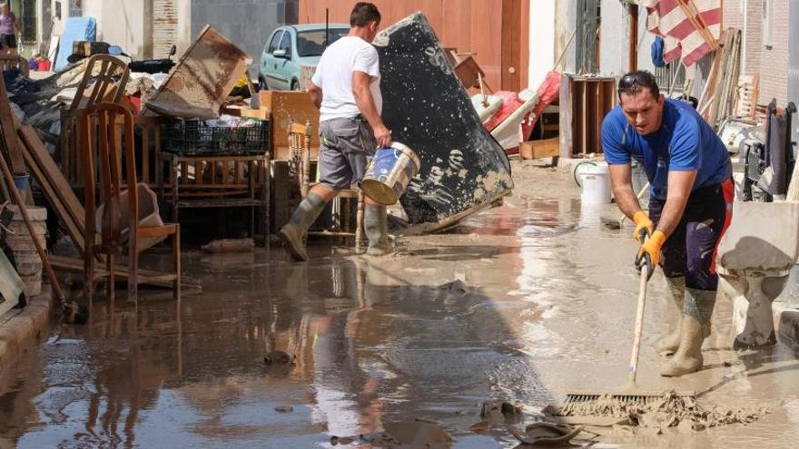 Un hombre retira el barro en una de las zonas más afectadas por la riada en Almoradí.