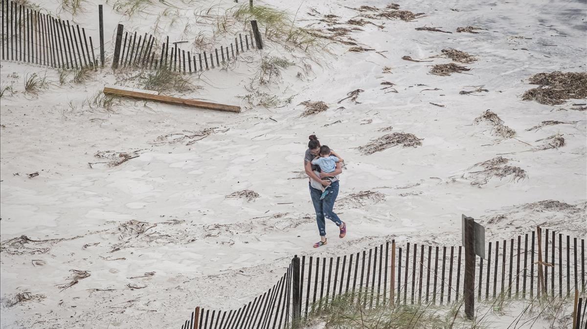 Una mujer sostiene a su hijo mientras azota el viento del huracán Sally. 
