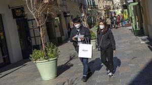 Dos clientes pasean por las tiendas de La Roca Village con mascarillas protectoras por miedo a contraer el coronavirus, este miércoles.
